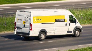 An InPost delivery van with yellow accent is seen driving on road.