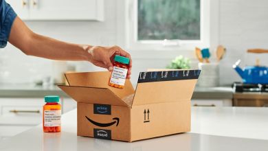 A person puts a prescription drug bottle into an Amazon box for shipping.