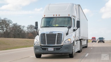 a closeup of a white tractor pulling a white trailer on a highway
