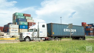a sleeper cab leaving port with an ocean container