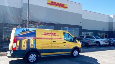 A yellow DHL Express van in front of a DHL service center.