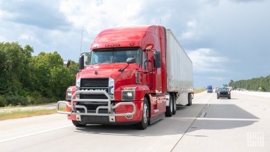 a red tractor pulling a trailer on a highway