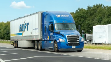 A blue Swift Transportation tractor pulling a trailer with a skirt