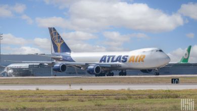 An Atlas Air Boeing 747 jumbo jet seen across an airport field from the front side on a sunny day.