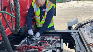 Clarios technician installing Battery Manager Pro monitoring hardware on a commercial truck battery at a fleet terminal