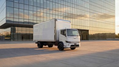 Harbinger HC Series Cab low-cab-forward medium-duty truck parked in front of a modern glass office building at sunset