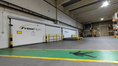 Inside an airport warehouse with PrimeFlight logo on doors.