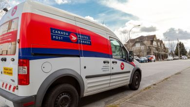 A red-white Canada Post delivery van parked on a suburban street.