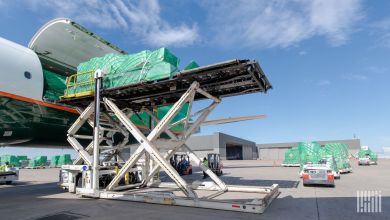 A hydraulic platform lifts a cargo pallet to the cargo entrance of a large freighter aircraft.