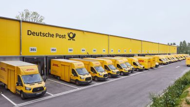 Yellow Deutsche Post mail terminal with yellow trucks parked alongside loading docks.
