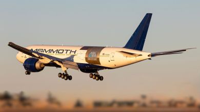 A Boeing 777, with airframe alterations for a new cargo door and Mammoth Freighters logo, comes in for landing with wheels down, as seen from rear.