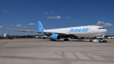 An Amazon Prime freighter aircraft with light blue accents is parked on an airport tarmac.