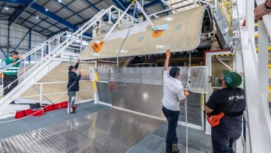 Machinists work to attach a large cargo door to an airframe at an Airbus plant.