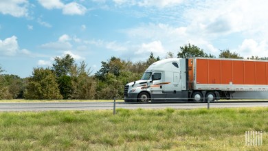 a white Schneider sleeper cab pulling an orange Schneider trailer