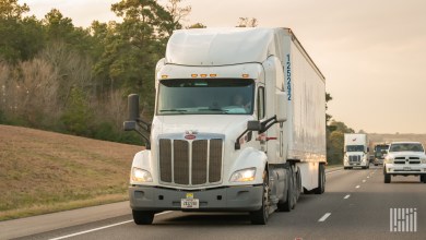 A white Pamt tractor pulling a trailer on a highway