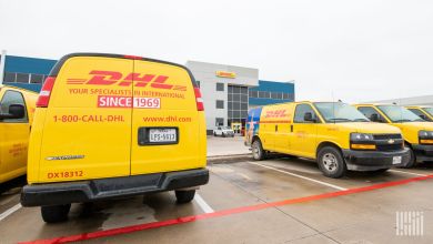 Yellow DHL Express delivery vans in a DHL parking lot.