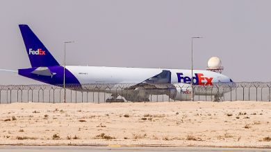 A purple-tail FedEx plane on a desert runway as seen from the side-rear angle.