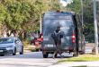 An Amazon delivery driver opens the door off the van on a neighborhood street with cars parked along the curb nearby.