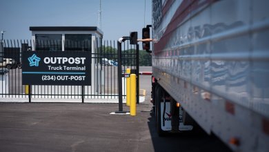 Driver interacts with Outpost’s gate kiosk at truck terminal as semi-truck pulls up to automated gate