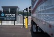 Driver interacts with Outpost’s gate kiosk at truck terminal as semi-truck pulls up to automated gate
