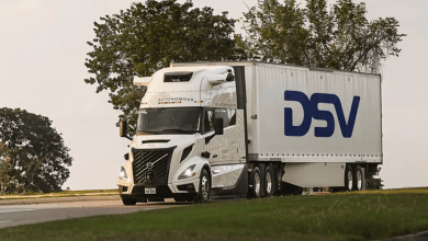 White Volvo VNL Autonomous semi-truck with large blue DSV logo on the trailer driving on a highway during the launch of autonomous freight operations between Dallas and Houston