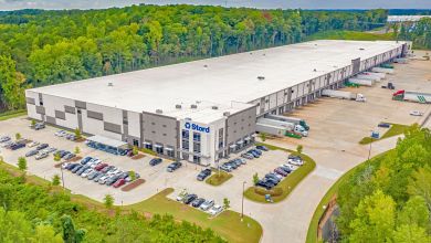 A large Stord warehouse surrounded by parking lots and trees.