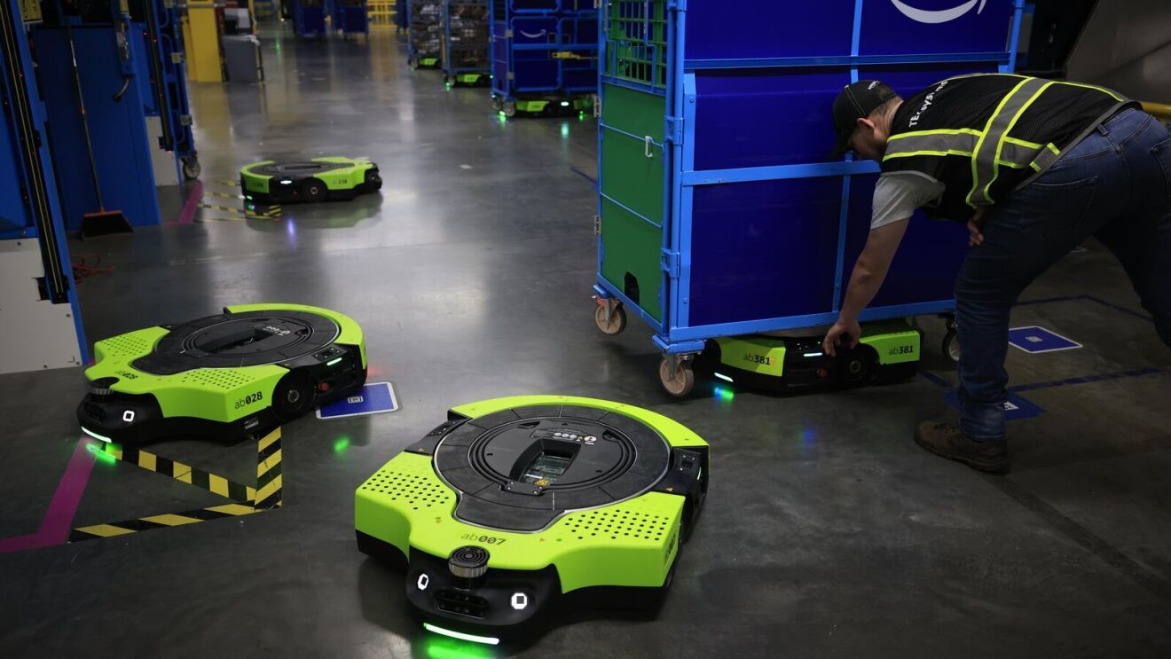 Green-and-black robotic saucers are moving carts of packages in Amazon fulfillment centers.