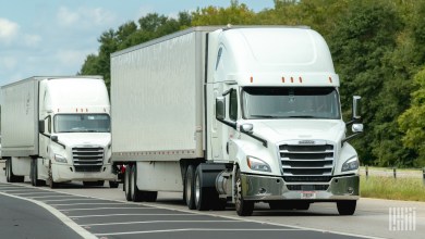 a pair of white sleeper cabs pulling trailers on a highway