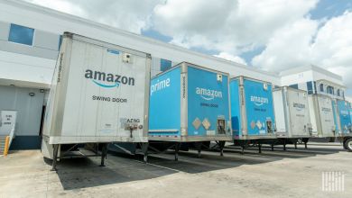 Amazon blue-and-white trailers parked at doors of a warehouse.