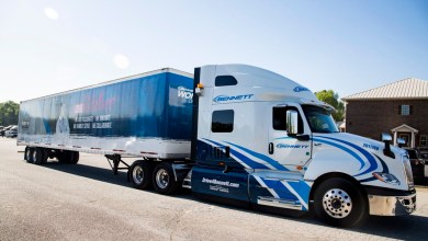 White and blue Bennett Family of Companies semi-truck pulling a dry van trailer featuring core values branding and Drive4Bennett.com contact information.