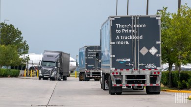 Multiple Amazon trailers being pulled by trucks near a warehouse
