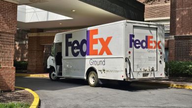 A FedEx delivery van is parked underneath an apartment building entrance canopy.
