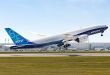 A large 777 jet in Boeing livery takes off from an airfield.