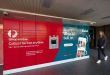 A view of a red Australia Post parcel locker with a an advertisement for Vinted e-commerce company.