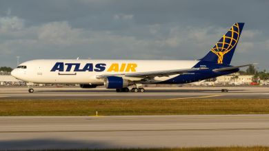 An Atlas Air cargo jet with puprle and yellow markings prepares for takeoff.