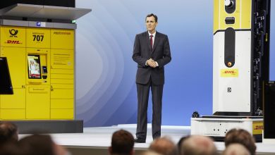 DHL CEO Tobias Meyer addressed an audience flanked by yellow DHL parcel locker system and other technology.