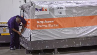 A FedEx worker drapes a pallet with a FedEx thermal blanket.