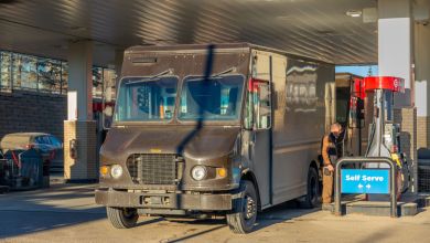 A brown UPS delivery van gets refueled at a fuel station.