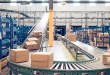 Parcels move on a large conveyor system through a warehouse.