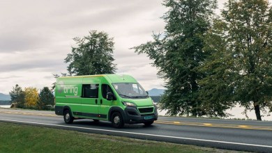 A green Posten Bring van travels on a two-lane highway.
