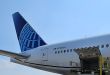 A close-up view of tail section of a United Airlines 777 jet with the rear cargo door open.