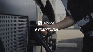 Worker in a high-visibility vest plugs a charging cable into an all-electric truck, with Einride and Flipturn logos overlaid.
