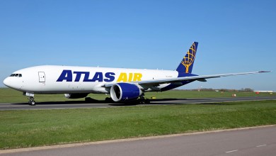A blue-and-gold tailed Atlas Air cargo jet moves on an airport road.