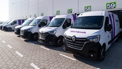 A line of Venipak parcel vans is parked against a warehouse wall.
