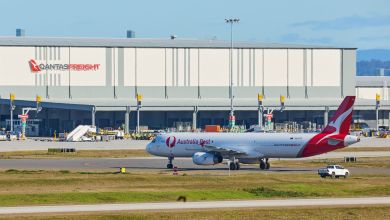 A red-tailed Australia Post cargo plane pulls up to a Qantas Freight airport terminal.