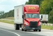 a red Saia daycab pulling a trailer on a highway