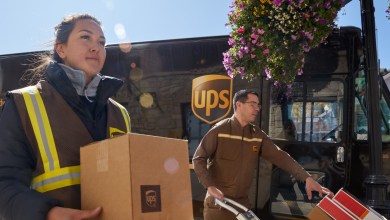 UPS drivers carry packages from their van to a small business.