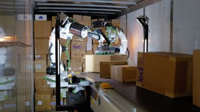 A robot loads boxes in truck compartment.