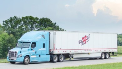 a baby blue Heartland tractor pulling a white Heartland trailer