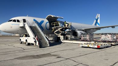 Side view of a GlobalX cargo jet with stairs to flight deck and cargo door open to accept pallets on a sunny day.